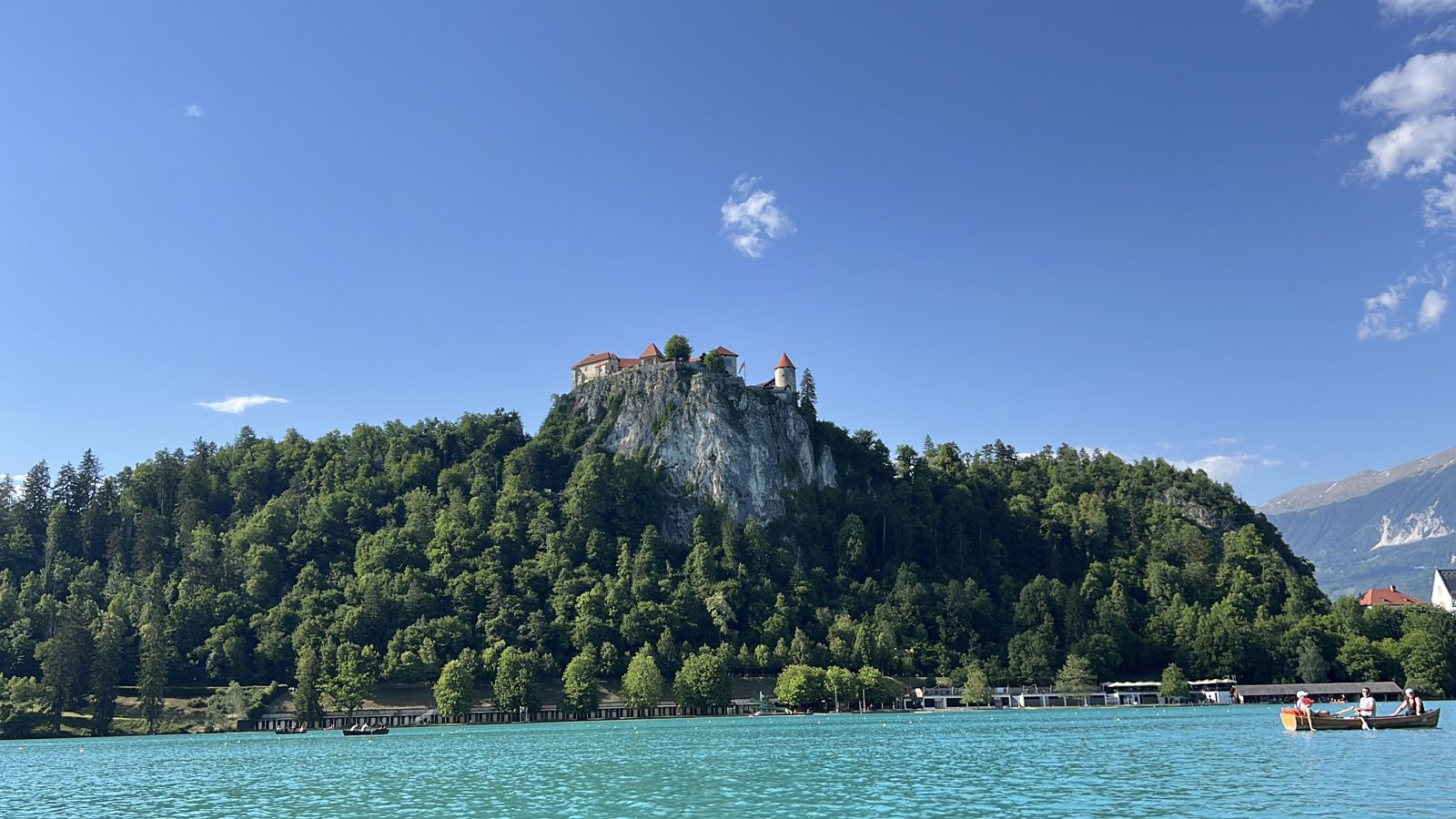Bled Castle on its cliff above the turquoise lake, seen from an electric boat during Ivan Verzoub's Slovenia site inspection for corporate incentive groups